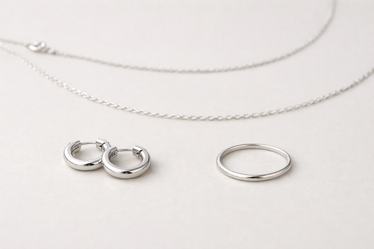 Assortiment kleine zilveren sieraden op een lichte neutrale achtergrond